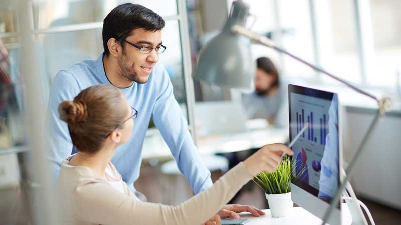 A man and woman who work with Tarun Jolly, M.D. looking at charts on a computer in New Orleans, LA