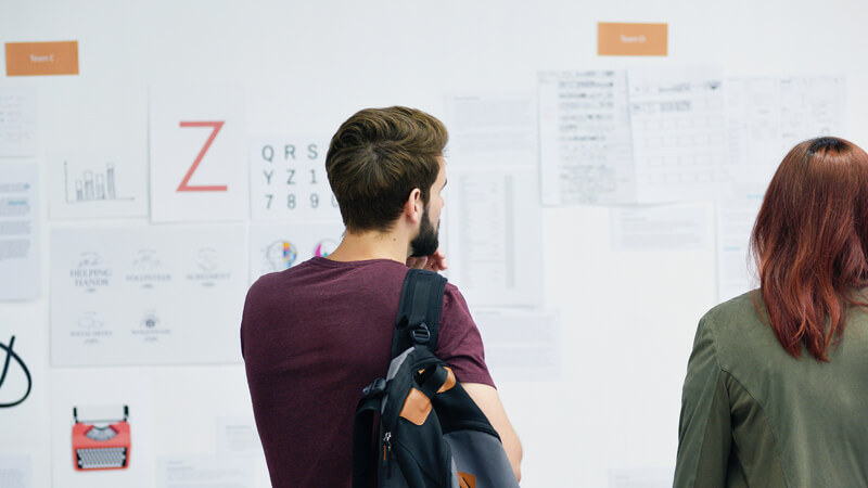 Two innovators who work with New Orleans, LA based Tarun Jolly, M.D. looking at information on a whiteboard