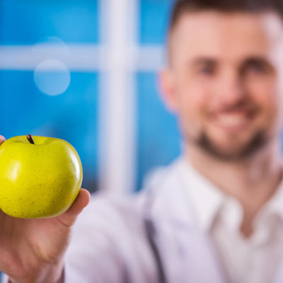 A doctor holding an apple representing medical innovators in New Orleans, LA who work with Tarun Jolly